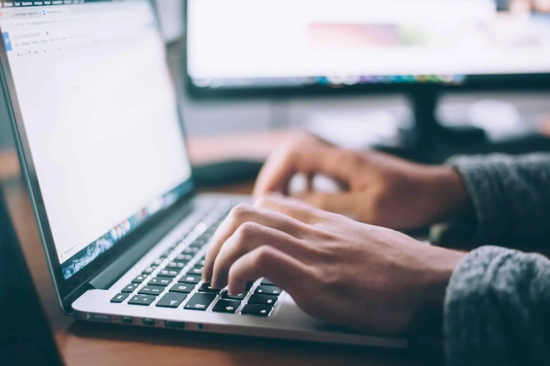 Primer plano de un teclado de ordenador con una mano escribiendo, simbolizando la productividad y el trabajo de oficina moderno.