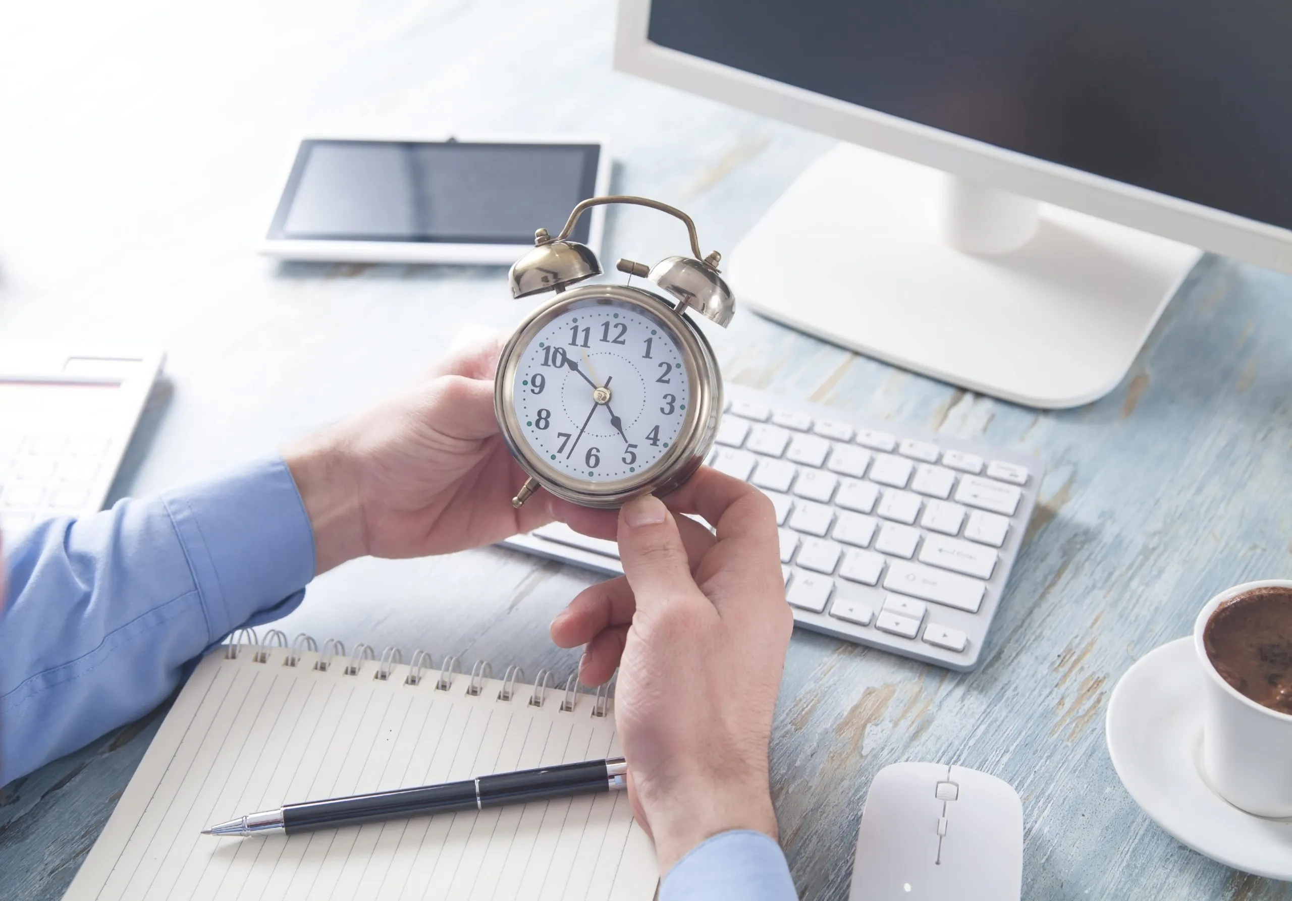 gestion-personal-tiempo-negocios Hombre de negocios preocupado sentado en una oficina con un despertador, simbolizando la urgencia de una eficiente gestión de personal.