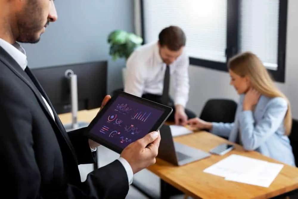 consultoria-tecnologica-estrategia-empresarial Consultores tecnológicos analizando un gráfico en una tablet, representando la estrategia clave en la transformación digital empresarial.